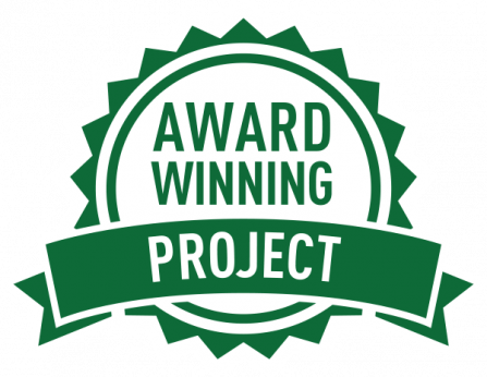 A green badge with white text reading Award Winning Project. The design features a circular shape with jagged edges and a banner across the center.