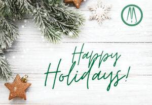 Festive greeting card featuring snow-dusted pine branches, golden star ornaments, and a snowflake on a white wooden background. Happy Holidays! is elegantly written in green text with a round green logo adorning the top right corner.