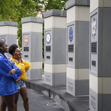 Two people observing a monument with plaques