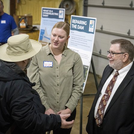 Three people having a discussion with posters in the background
