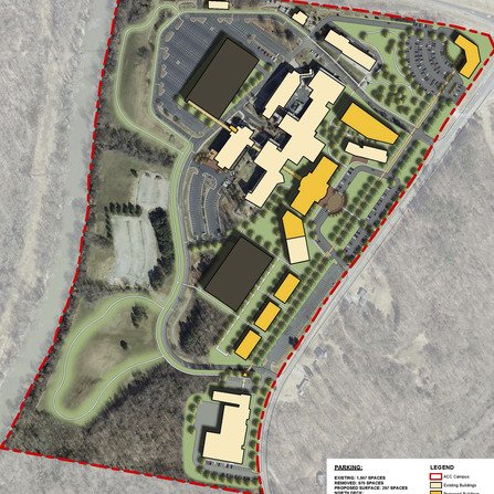 Aerial view of a large campus plan surrounded by trees, with multiple buildings in various colors. Roads and parking lots are visible, and paths connect the structures. A red dashed line marks the boundary. A legend explains the color coding.