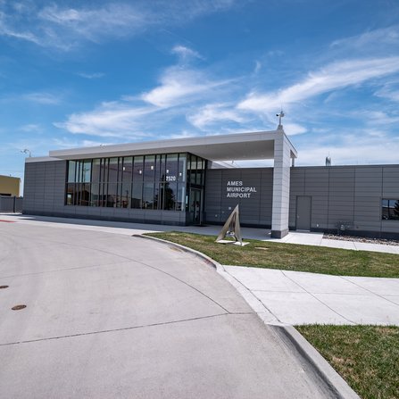 Airport building with glass windows and a metal triangle sculpture in front