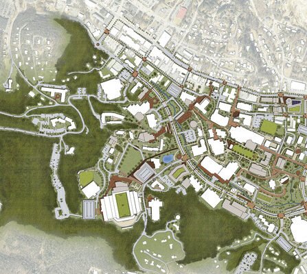 Aerial view of a detailed urban landscape map, featuring various buildings, sports fields, parking lots, and roads. Green areas surround a complex network of streets and structures, indicating a mix of urban and natural spaces.