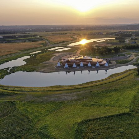 A cultural center surrounded by sunset, ponds, and native tepees