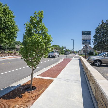 Sidewalk with a tree and brick retaining wall
