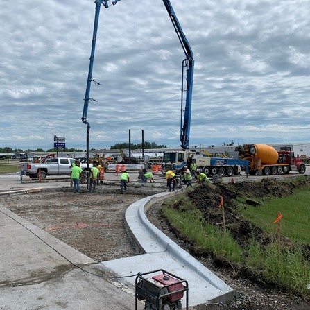 A group of construction workers are pouring concrete from a cement truck at a construction site.