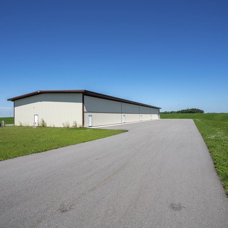 A spacious airport hangar with a concrete lot and lush green surroundings