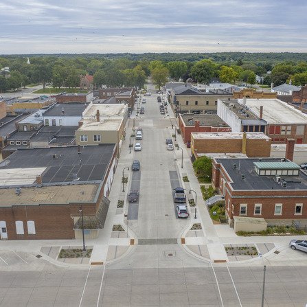 A serene downtown scene with parked cars and buildings lining the side.