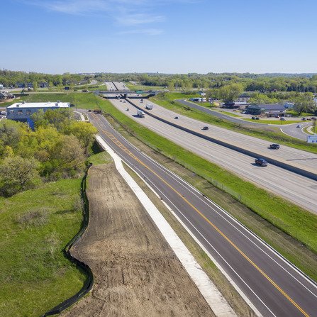 Aerial view of a newly paved road running alongside the busy interstate