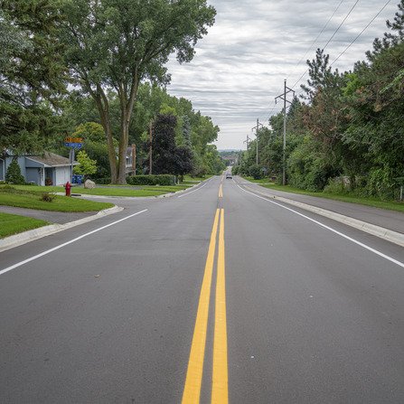 Newly paved road and bike path with brick retaining wall running alongside