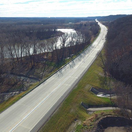 Aerial view of a 4-lane highway cutting through a dense forest