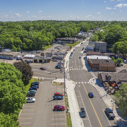 Aerial view of a business area with buildings, parking, roads, and greenery