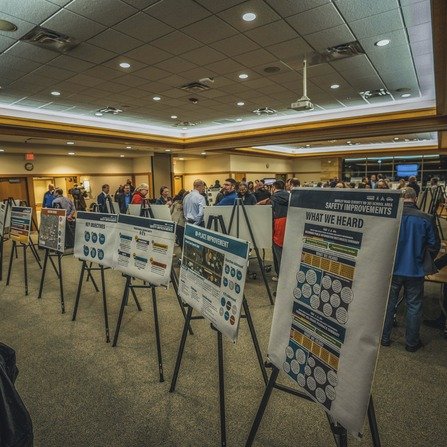 Survey and information boards, attracting a crowd of engaged individuals.