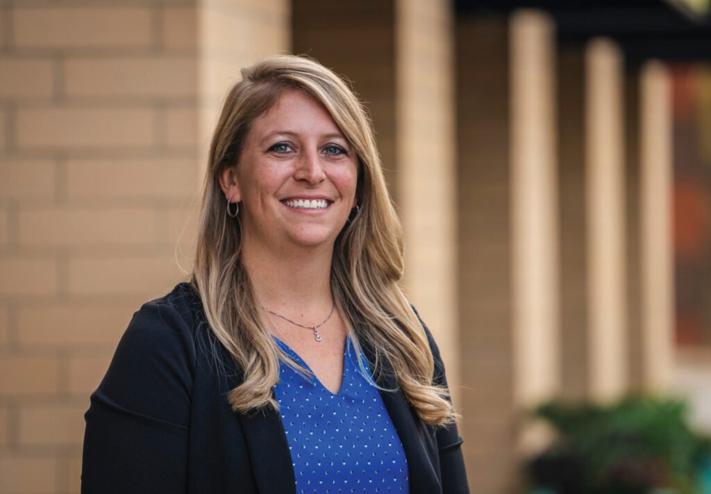 woman in blue shirt and black blazer smiling at camera