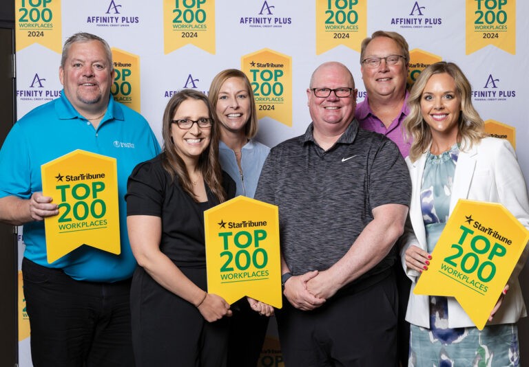 Top 200 Workplaces of Minnesota Luncheon with a group of people holding yellow signs