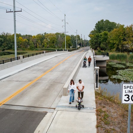 Pedestrians crossing bridge over narrow causeway