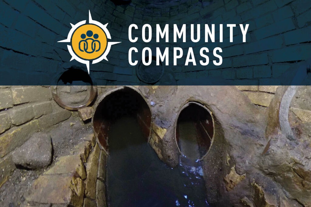A brick-lined underground tunnel with murky water flows through two arched openings. The top of the image features the Community Compass logo and text on a blue background.